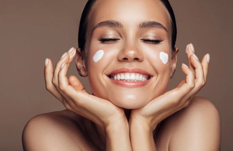 Donna felice applica la crema per il viso