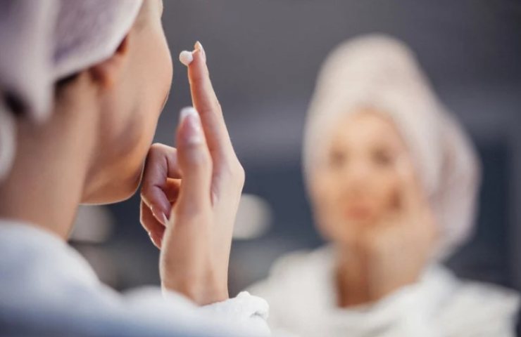 Donna mette la crema sul viso 